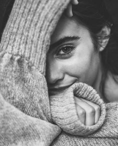 a black and white photo of a woman wrapped up in a blanket looking at the camera