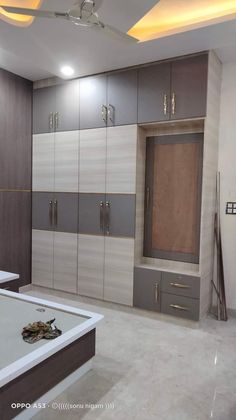 an empty room with cabinets and drawers on the wall, in front of a bathtub