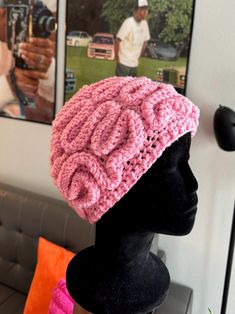 a crocheted pink hat sitting on top of a mannequin's head