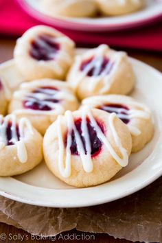 small cookies with white icing on a plate next to a red napkin and cup of coffee