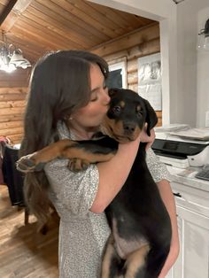 a woman holding a dog in her arms while standing next to a stove top oven