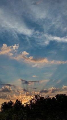 the sun is setting behind some trees and clouds