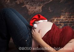 a pregnant woman wearing a santa hat laying on her stomach