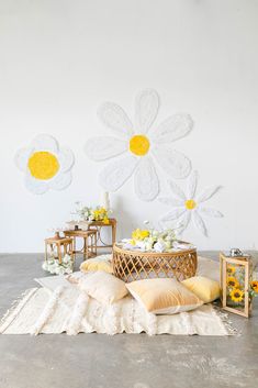 a table topped with pillows and flowers next to a basket filled with yellow daisies