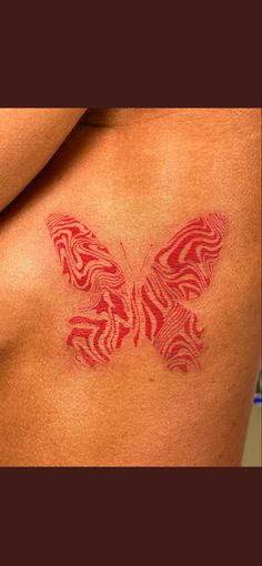 a woman's back with a red butterfly tattoo on her left shoulder and chest