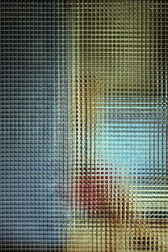 an abstract image of blue, yellow and red colors on a meshed glass surface