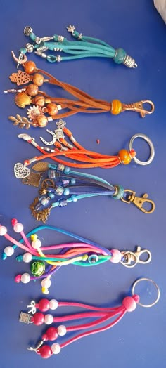 a collection of beaded key chains on a blue surface with beads and charms attached to them