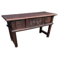 an old wooden table with two drawers on one side and a carved design on the other