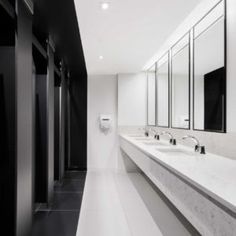 a long bathroom with two sinks and mirrors on the wall next to urinals