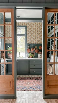 an open door leading to a kitchen with potted plants on the counter and cabinets