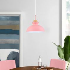 a dining room table with pink chairs and a painting on the wall in the background