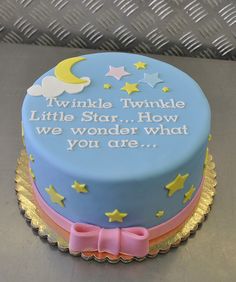 a blue cake with yellow stars and a pink bow on the top that says twinkle little star how we wonder what you are