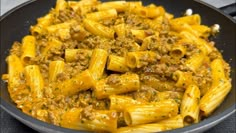 a skillet filled with pasta covered in sauce and ground meat, on top of a table