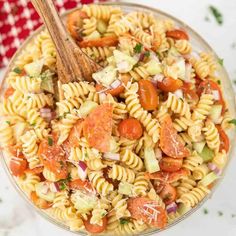 a bowl filled with pasta salad next to a red and white checkered table cloth