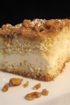 a piece of cake sitting on top of a white plate next to some walnuts