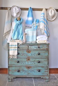 an old dresser with towels and hats on it