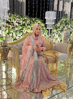 a woman sitting on top of a couch wearing a pink and gold dress with sequins