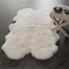 a white sheepskin rug sitting on top of a tile floor next to a table