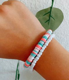 a woman's arm with two bracelets on it and a plant in the background