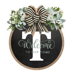 a welcome sign with a bow and flowers on the front of it, that says welcome to our home