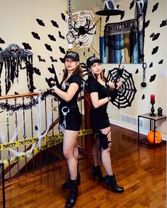 two women dressed up in costumes standing next to each other with halloween decorations on the wall behind them