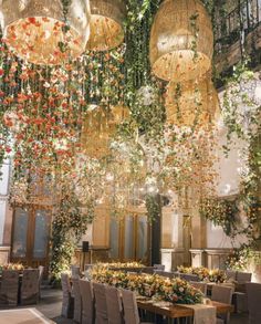 an indoor dining area with chandeliers hanging from the ceiling and flowers on the walls