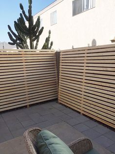 a wooden fence next to a patio with a couch and cactus in the back ground