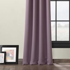 a window with a purple curtain next to it and two pictures on the floor in front