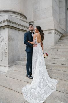 a bride and groom standing on the steps in front of an ornate building with columns