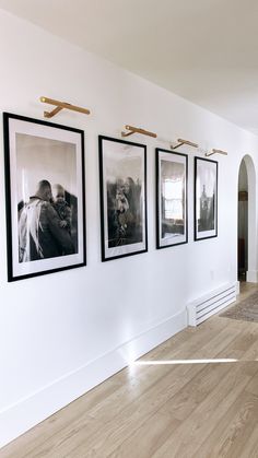 three black and white pictures hang on the wall in an empty room with hard wood flooring