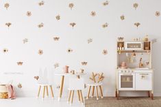 a room with white furniture and pink flowers on the wall, including two small children's chairs