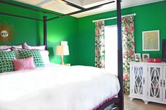 a bedroom with green walls, white bedding and pink accents on the nightstands