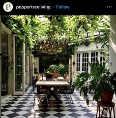 an outdoor dining area with black and white checkered tile flooring, potted plants on the table