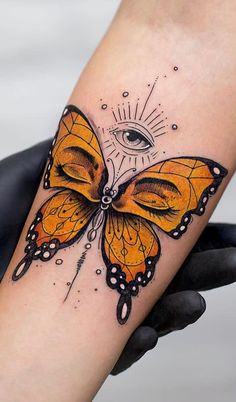 a butterfly tattoo with an eye on it's back arm and the wings are yellow