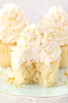 two cupcakes with white frosting and sprinkles on a plate