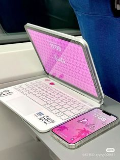 an open laptop computer sitting on top of a white desk next to a cell phone