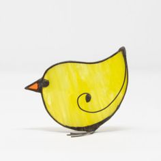 a small yellow bird sitting on top of a white table next to a black object