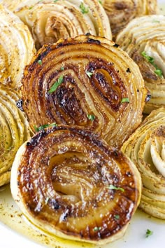 some onion rings on a white plate with parsley sprinkled around them and garnished with seasoning