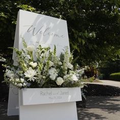 a welcome sign with white flowers and greenery