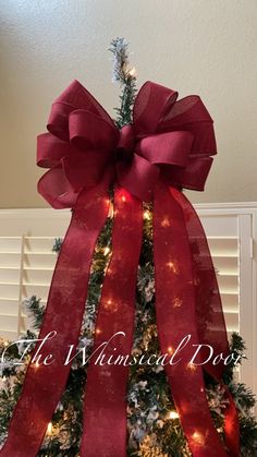 a christmas tree decorated with red ribbon and lights