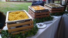 several trays of food on a table in front of a fenced backyard area