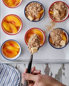 a person holding a spoon with some food in it on top of a baking tray