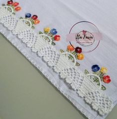 a close up of a white table cloth with flowers and lace on the edge,