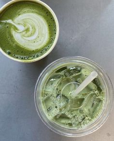 two cups filled with green liquid next to each other on top of a gray table