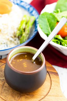 a bowl of soup next to a plate of rice and salad