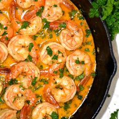 a skillet filled with shrimp and garnished with parsley on the side