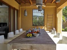 a table with fruit on it in front of an open patio door and large window