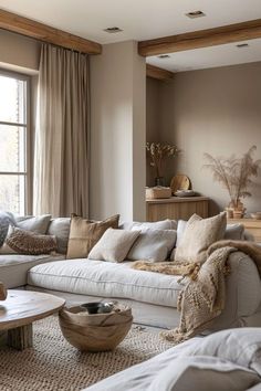 a living room filled with lots of furniture and pillows on top of a couch next to a window