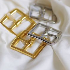 three metal buckles laying on top of a white sheet