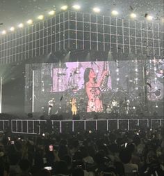 the stage is lit up with lights and confetti as people are standing in front of it